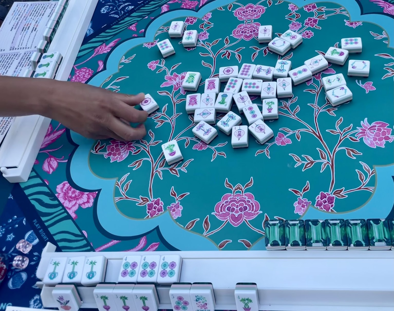 Colorful mahjong tiles spread across a floral mat